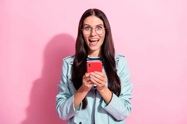 Foto van verbaasd vrolijke vrouw dragen casual outfit houden telefoon als reactie geïsoleerd op roze kleur achtergrond — Stockfoto