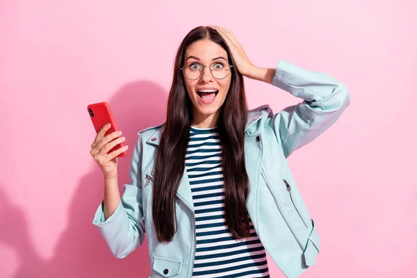 Foto van geschokte jonge vrouw houd handen hoofd telefoon ongelooflijk commentaar geïsoleerd op roze kleur achtergrond — Stockfoto