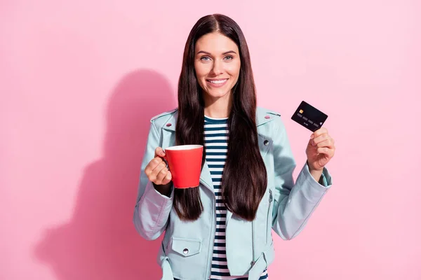Foto av attraktiv charmig flicka hålla kaffemugg kreditkort isolerad på pastell rosa färg bakgrund — Stockfoto