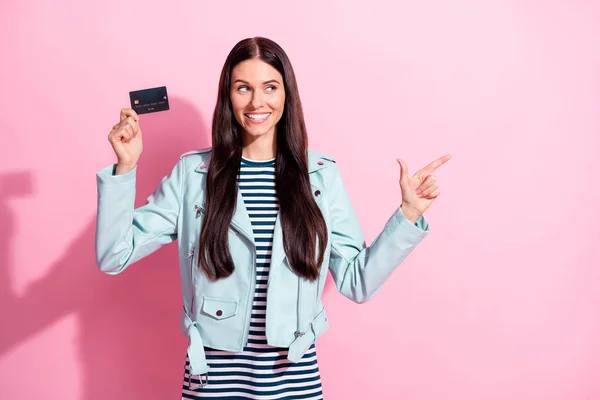 Foto av brunett ung glad kvinna ser punkt tomt utrymme hålla kreditkort isolerad på rosa färg bakgrund — Stockfoto