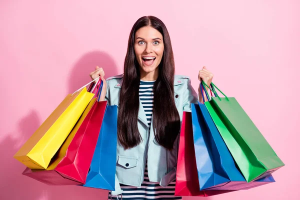 Foto van verrast vrolijk charmant meisje houden boodschappentassen verkoop korting geïsoleerd op pastel roze kleur achtergrond — Stockfoto