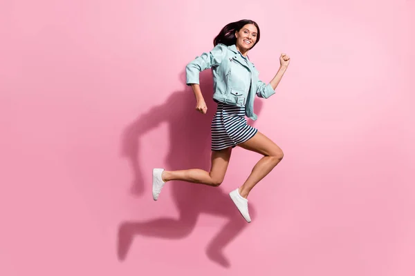 Full length photo of sweet pretty young girl dressed blue jacket hurrying running jumping isolated pink color background