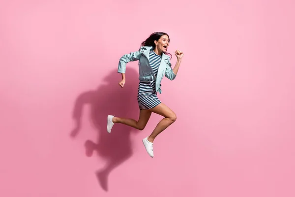 Pleine longueur photo de jolie adorable jeune fille habillée veste bleue se dépêchant de courir sautant isolé fond de couleur rose — Photo