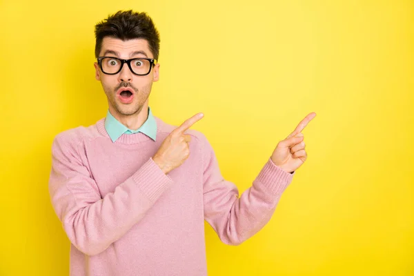 Zdjęcie młodego przystojnego zszokowanego zaskoczonego mężczyzny w okularach reklamowych produkt izolowany na żółtym tle koloru — Zdjęcie stockowe