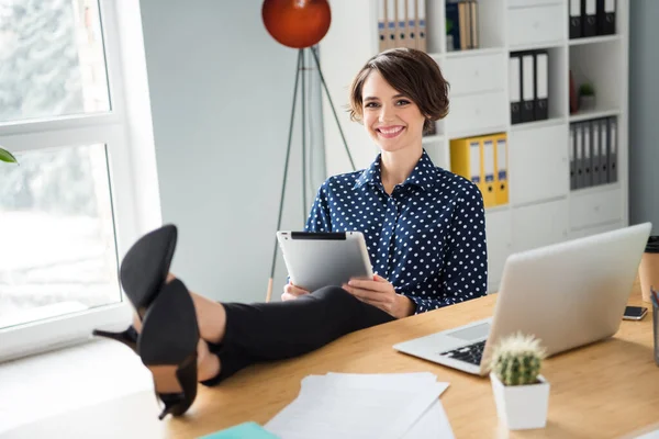 Portrét atraktivní veselá dívka režisér sedí v křesle uvedení nohy na stůl pomocí ebook na lehkém pracovišti vnitřní — Stock fotografie