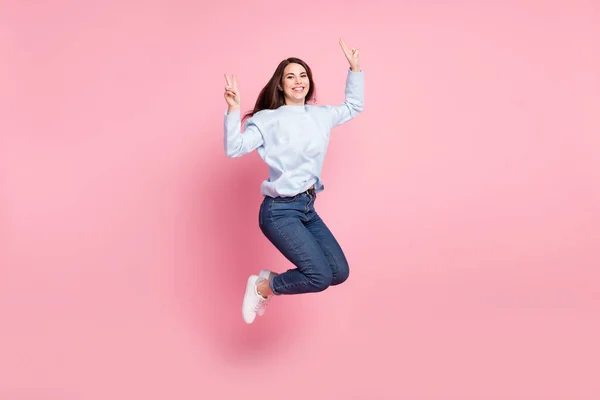 Full storlek profil foto av trevlig optimistisk lång frisyr brunett dam hoppa visar v-tecken bära blå tröja isolerad på rosa bakgrund — Stockfoto