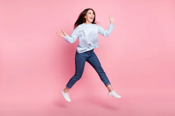 Foto de perfil de tamaño completo de bonito optimista largo peinado morena dama salto mirada espacio vacío desgaste suéter azul aislado sobre fondo rosa —  Fotos de Stock