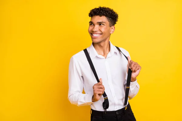 Foto van knappe man kijken lege ruimte glanzende glimlach dragen shirt bretels geïsoleerde gele kleur achtergrond — Stockfoto