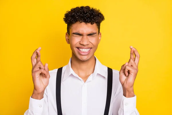 Foto retrato de homem afro-americano com olhos fechados cruzou os dedos isolados em fundo colorido amarelo vívido — Fotografia de Stock