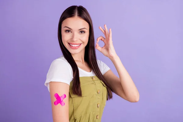 Foto de morena feliz mujer mostrar signo de bien desgaste casual traje vacuna aprobar aislado sobre fondo de color violeta —  Fotos de Stock
