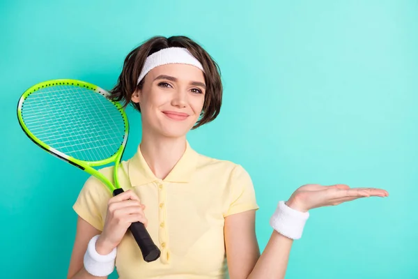 Portret van aantrekkelijke sportieve vrolijke meisje houden in de hand racket kopiëren ruimte op palm geïsoleerd over heldere teal turquoise kleur achtergrond — Stockfoto