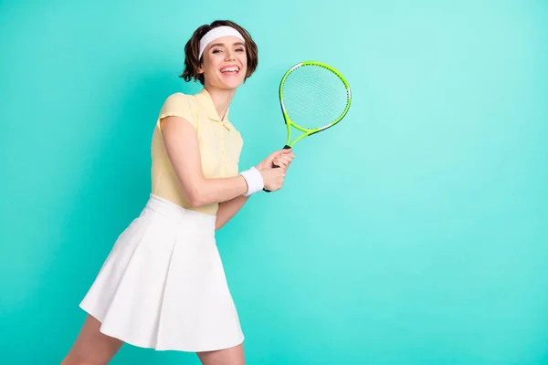 Портрет привлекательной спортивной веселой девушки, играющей в теннис, развлекающейся на ярко-бирюзовом фоне — стоковое фото