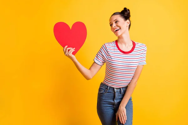 Fotografie optimistické brunetka Lady hold vzhled srdce nosit tričko džíny izolované na jasně žluté barvy pozadí — Stock fotografie