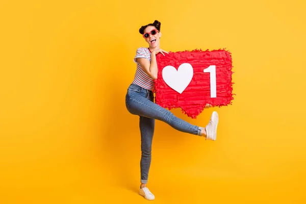 Foto de la joven funky infantil usar camisetas rayadas gafas oscuras bailando sosteniendo grandes como signo aislado color amarillo fondo — Foto de Stock