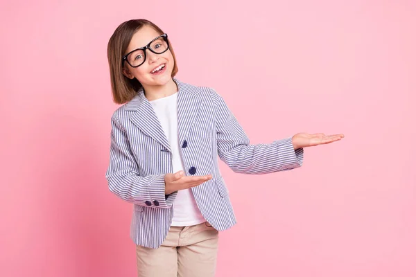 Retrato de atractiva chica intelectual alegre aprendiz demostrando en palmeras espacio de copia aislado sobre fondo de color pastel rosa —  Fotos de Stock