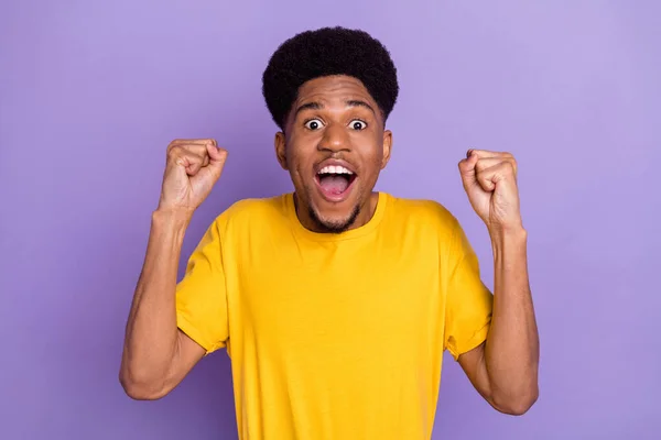 Фото счастливого удивленного шокированного темная кожа молодой человек поднять кулаки победителя изолированы на фиолетовом фоне — стоковое фото