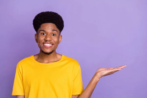 Foto van positieve jonge donkere huid gelukkig man houd hand lege ruimte nieuws geïsoleerd op paarse kleur achtergrond — Stockfoto