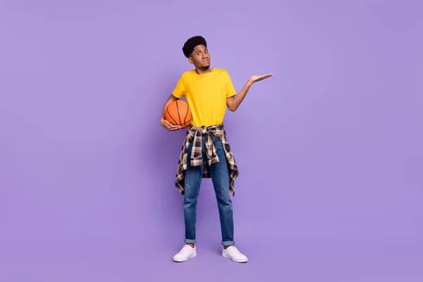 Ganzkörpergröße Ansicht der attraktiven verwirrten Kerl halten Ball Achselzucken Schultern isoliert über violett lila Farbe Hintergrund — Stockfoto