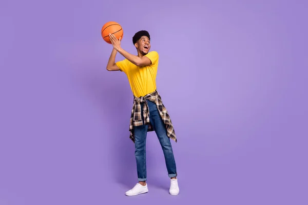 Foto in voller Größe von glücklichen afroamerikanischen jungen Mann suchen leeren Raum halten Ball isoliert auf lila Farbhintergrund — Stockfoto
