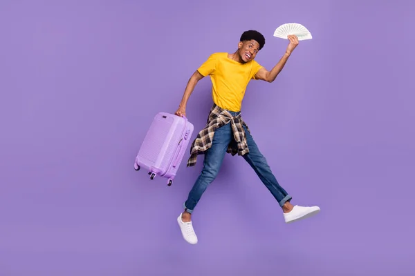 Full längd kroppsstorlek syn på attraktiv glad kille hoppar bär kontanter bagage isolerad över violett lila färg bakgrund — Stockfoto