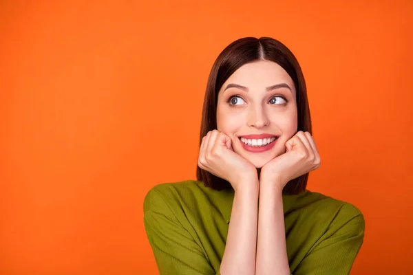 Foto von süßen brünetten Frisur junge Dame Hände Wangen sehen leer Raum tragen grünes Hemd isoliert auf orangefarbenem Hintergrund — Stockfoto