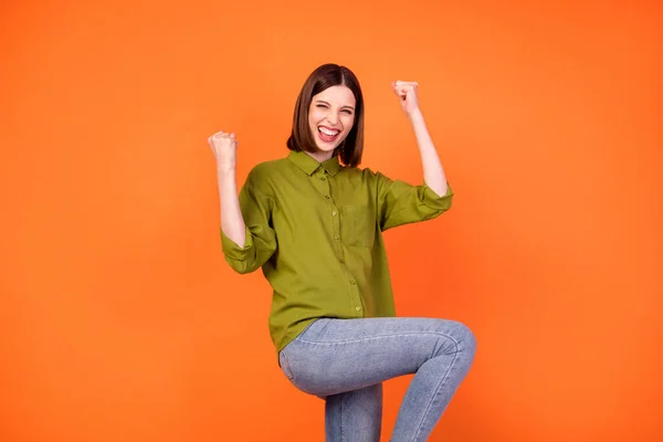 Foto de hooray bob hairdo jovem senhora mãos punhos usar camisa verde isolado no fundo cor de laranja — Fotografia de Stock