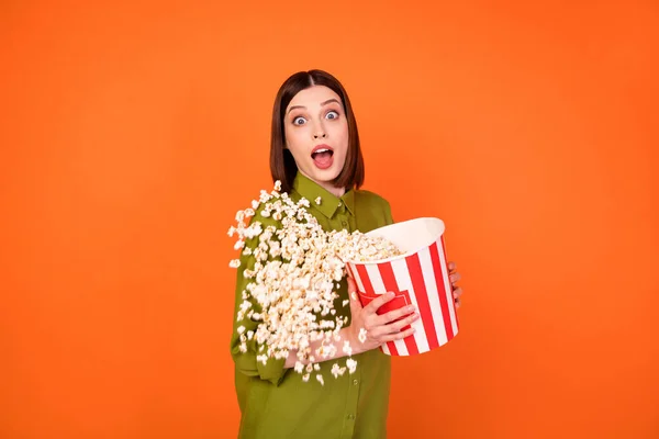 Foto van opgewonden brunette millennial dame houden pop maïs dragen kaki shirt geïsoleerd op oranje kleur achtergrond — Stockfoto