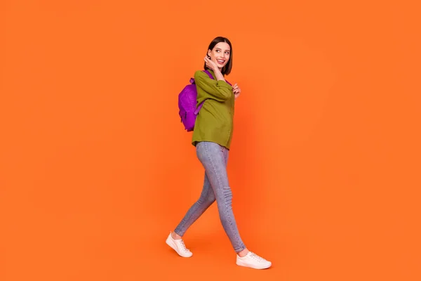 Полный профиль тела фото прекрасной брюнетки Millennial леди пойти посмотреть пустой космос носить мешок джинсы рубашки изолированы на оранжевом фоне цвета — стоковое фото