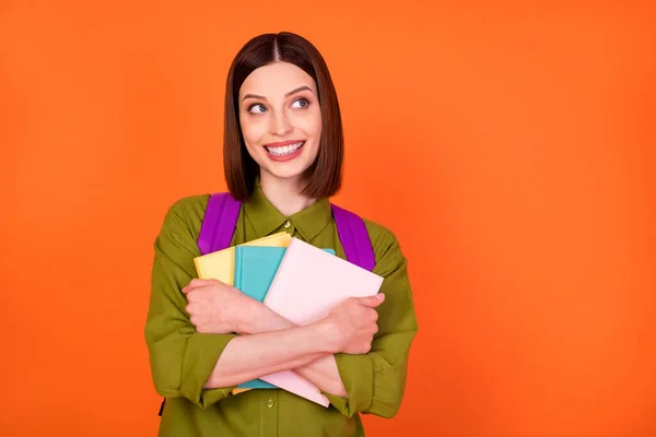 Foto di smart bruna signora abbraccio libri guardare vuoto spazio usura borsa camicia isolato su sfondo di colore arancione — Foto Stock