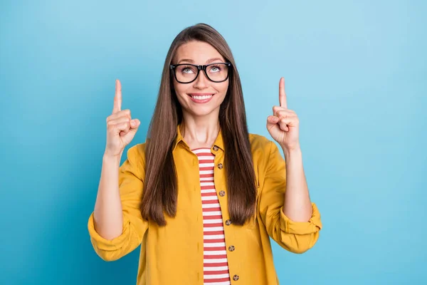 Фото молодой женщины счастливый позитивный взгляд улыбка указывает палец вверх реклама советуем решение выбрать изолированы на синем фоне цвета — стоковое фото
