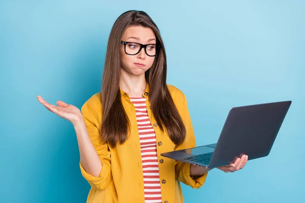 Foto de jovem segurar as bochechas respiração incerto questionado relatório incerto olhar laptop isolado sobre fundo de cor azul — Fotografia de Stock