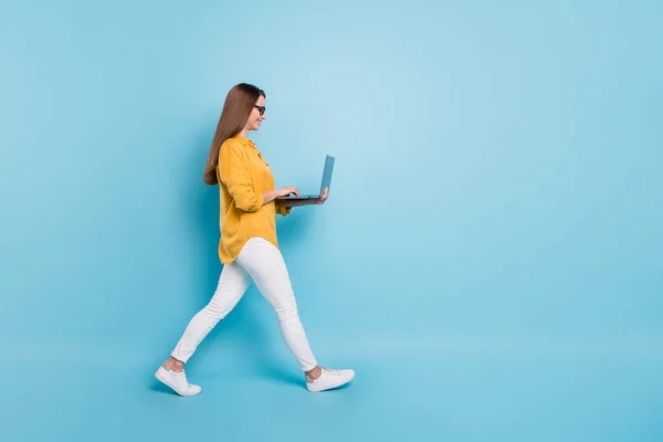 Perfil de comprimento total foto lateral da mulher atraente segurar laptop andar espaço vazio isolado no fundo de cor azul — Fotografia de Stock