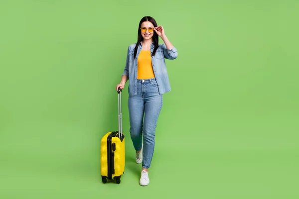 Фотография счастливой красавицы в полный рост в аэропорту с рюкзаком на зеленом фоне — стоковое фото