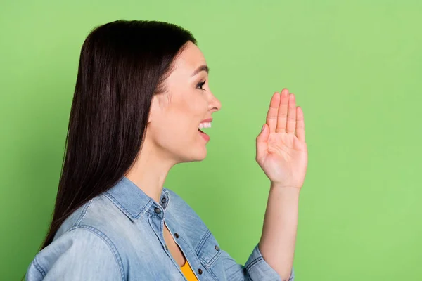 Perfil foto de engraçado agradável marrom penteado senhora falar mão boca desgaste jeans camisa isolada no fundo verde — Fotografia de Stock