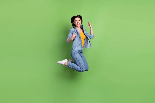 Foto de perfil de tamaño completo de cool brown hairdo lady jump show rock sign wear jeans shirt sneakers isolated on green background —  Fotos de Stock