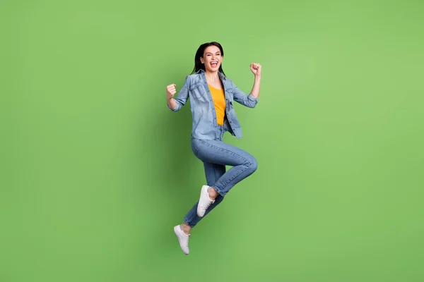 Full size profilo foto di hooray marrone acconciatura signora salto indossare jeans camicia scarpe da ginnastica isolato su sfondo verde — Foto Stock