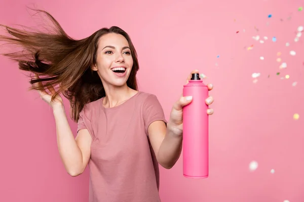 Photo of pretty excited young lady wear casual outfit smiling applying glitter hair spray isolated pink color background — Stock Photo, Image