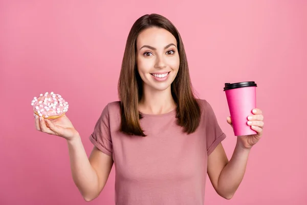 Retrato de menina alegre atraente comer delicioso donut bebendo cappuccino isolado sobre cor pastel rosa fundo — Fotografia de Stock