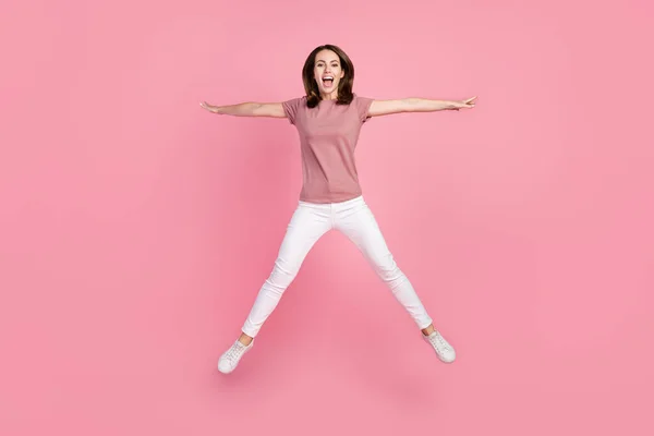 Full storlek foto av rolig brunett ung dam hoppa slitage t-shirt jeans isolerad på rosa färg bakgrund — Stockfoto