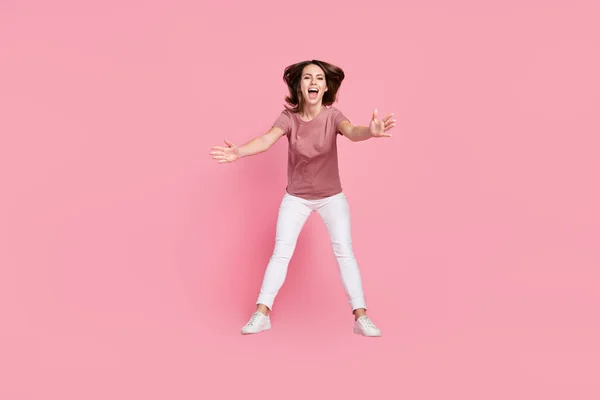깡충깡충 뛰어오르는 매력적 인 소녀가 분홍색 파스텔 색 배경을 가지고 재미있게 놀고 있는 모습의 전체 몸길이 — 스톡 사진