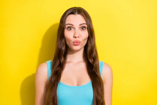 Foto portrét dívka s dlouhými vlasy v modré tílko posílání vzduchu polibek s našpulenými rty izolované jasně žluté barvy pozadí — Stock fotografie