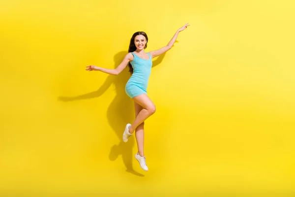 Foto de longitud completa de alegre peinado morena joven dama salto usar vestido de color verde azulado aislado sobre fondo de color amarillo vivo —  Fotos de Stock