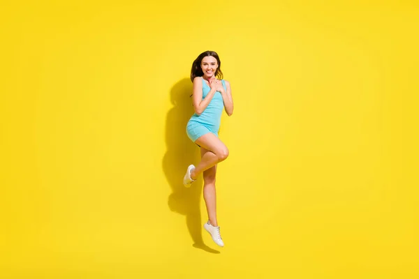 Foto de tamaño completo del peinado morena impresionado joven dama salto usar vestido de color verde azulado aislado sobre fondo de color amarillo vivo — Foto de Stock