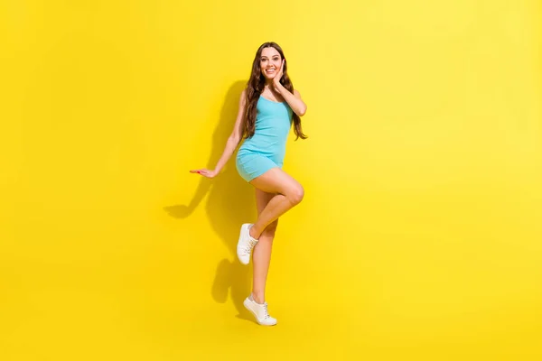 Взгляд в полный рост на привлекательную жизнерадостную девушку, танцующую весело позируя на ярко-желтом фоне — стоковое фото