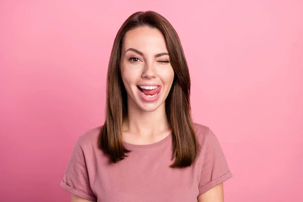 Foto de jovem mulher muito doce vestida roupas casuais sorrindo piscando mostrando língua isolado cor de fundo rosa — Fotografia de Stock