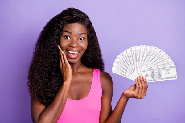 若い興奮アフロ女性の写真ショックを受けたホールドお金現金ドル豊かな紫色の背景に孤立 — ストック写真