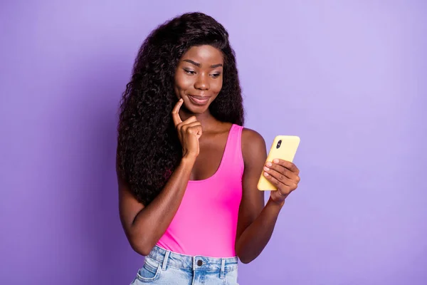 Foto portret van Afrikaans Amerikaans nieuwsgierig meisje met telefoon in een hand geïsoleerd op pastel roze gekleurde achtergrond — Stockfoto