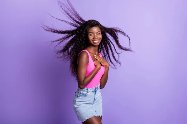 Foto retrato de mulher afro-americana com cabelo voador tocando peito isolado no fundo de cor rosa pastel — Fotografia de Stock