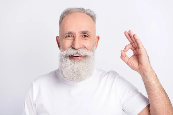 Photo of cheerful positive old man hold hand show okay sing smile recommend isolated on grey color background —  Fotos de Stock