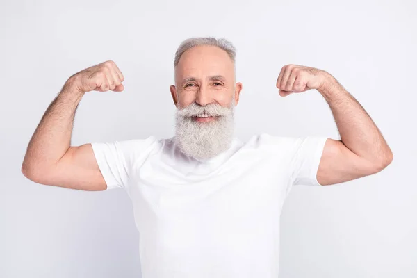Portrait of positive grey hair beard old man show muscles wear white t-shirt isolated on grey color background —  Fotos de Stock